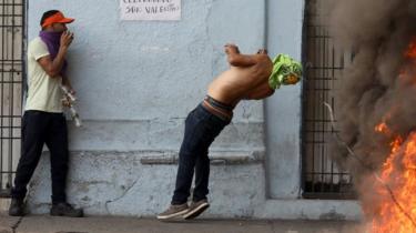 A demonstrator hits a barbed wire while clashing with security forces in Urena, Venezuela