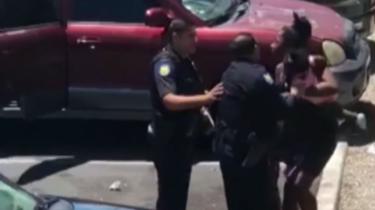 Police officers confront a woman holding a baby