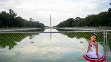 A visitor stands in front of temporary fencing installed along the National Mall as set up continues for President Donald Trump's "Salute to America"