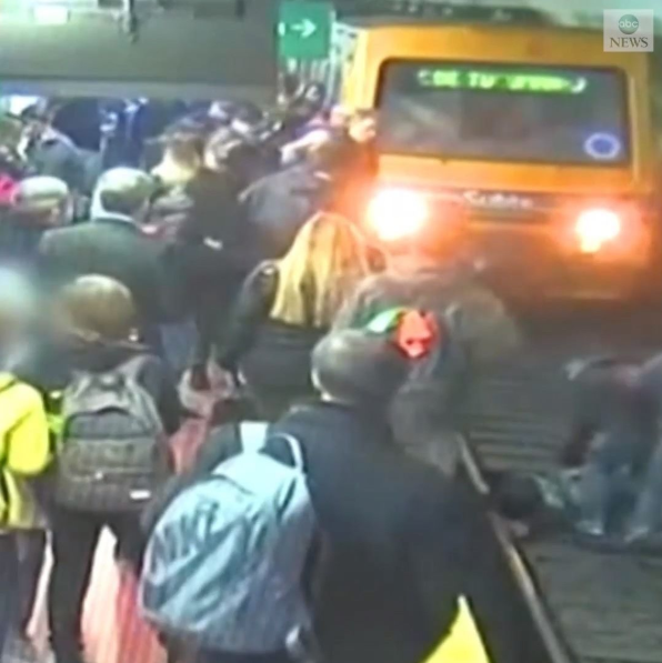 Crowd rescue woman after she fell into the path of an oncoming train (video)