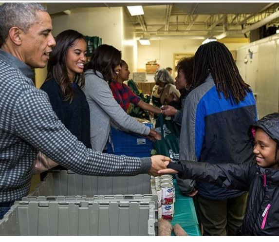 Barack Obama and his family pictured distributing food to people to celebrate Thanksgiving