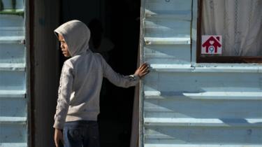 A South African stands next to a home in the Laan settlement in Strandfontein, Cape Town, South Africa.