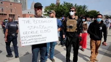 Armed men, one carrying a sign reading "The Boogaloo stands with George Floyd", are seen as protesters rally against the death in Minneapolis police custody of George Floyd, in Detroit, Michigan (May 30, 2020)