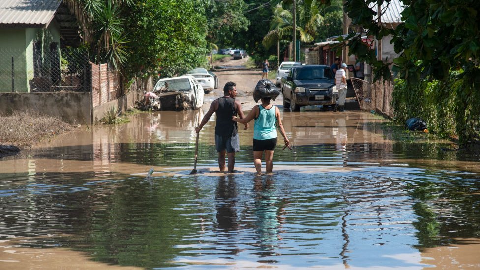 Couple wade through flooded street in La Lima, Honduras, on 8 November 2020