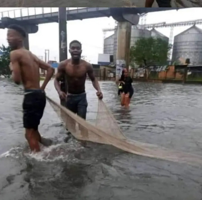 Youths bring out net to fish close to government house in Rivers state as streets flood following heavy rain