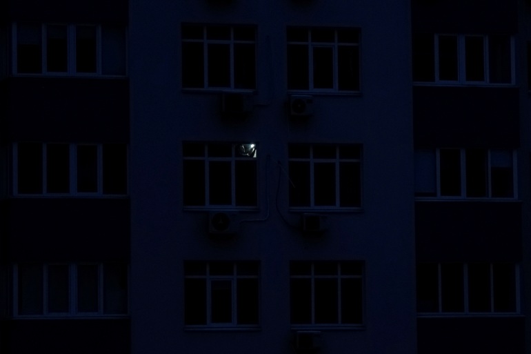 A man with a torch in the darkness of his flat in Kyiv, Ukraine.