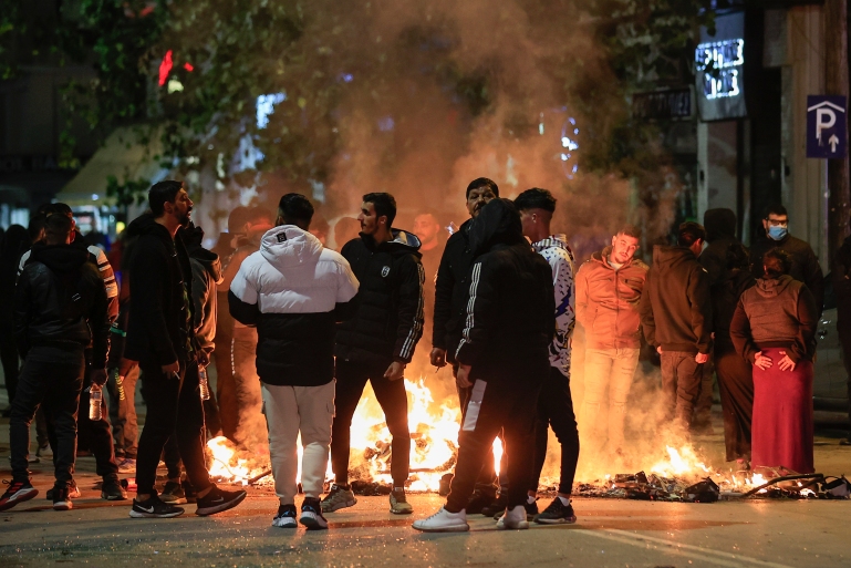 People blocking a main road set fire to rubbish bins outside the Ippokrateio General Hospital, in Greece's second largest city of Thessaloniki, on Monday, Dec 5, 2022. Dozens of Roma men protested Monday outside a hospital in northern Greece where a Roma teenager was being treated in critical condition, having been shot by police in a road chase after he allegedly drove off from a gas station without paying. (AP Photo/Dimitris Tosidis)