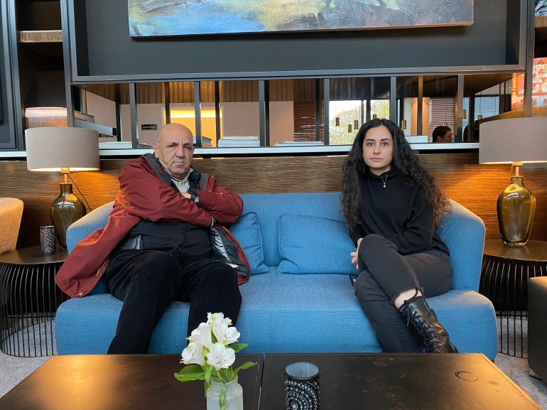 A photo of two people sitting next to each other on a sofa.