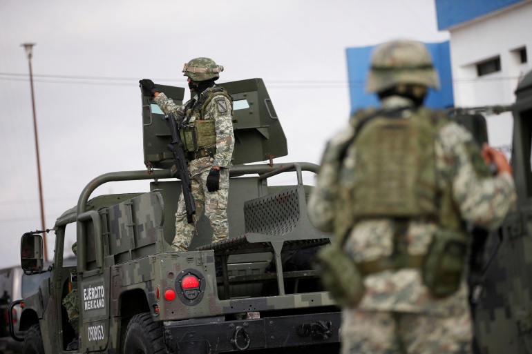 Soldiers stand guard as they repatriate the bodies of Americans killed in a kidnapping in northern Mexico