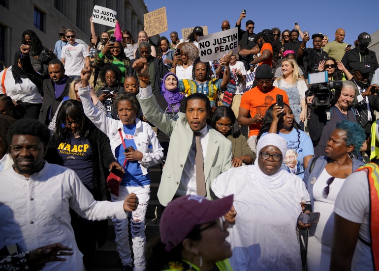 Justin Jones, surrounded by supporters, raises a fist in solidarity