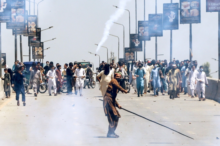 A supporter of Pakistan's former Prime Minister Imran Khan throws stones towards police during a protest against Khan's arrest, in Peshawar