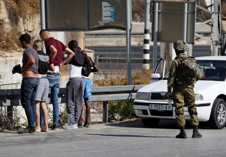 An Israeli soldier checks Palestinians at a checkpoint in Hebron in the Israeli-occupied West Bank 