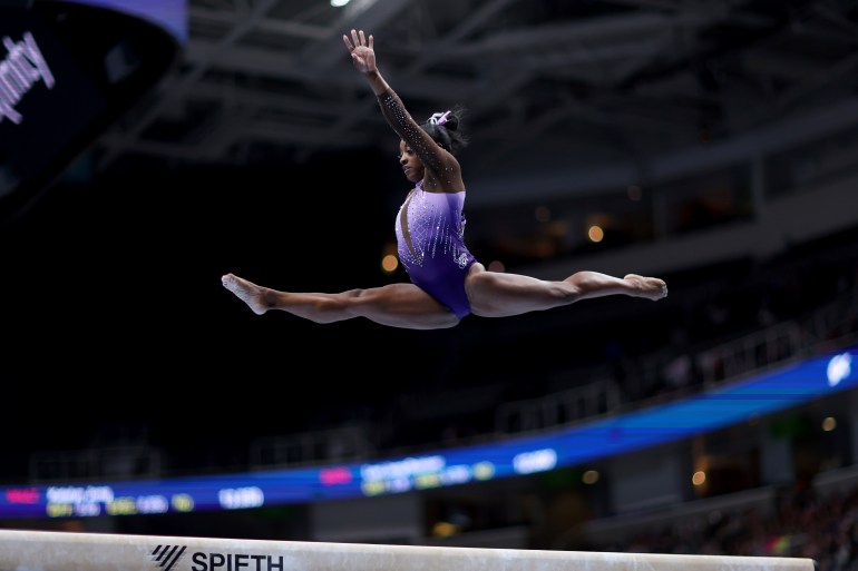 Simone Biles competing on the balance beam. 