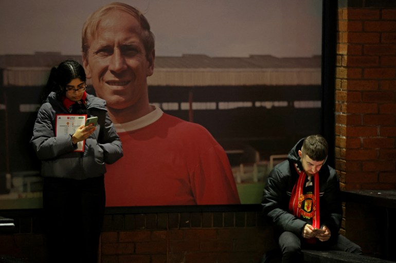 Fans infront of an image of former player Bobby Charlton