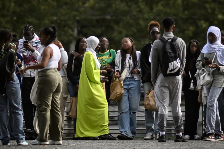 A young woman wearing an Abaya (C) speaks with others on a street in Nantes, western France on August 31, 2023. - The French government's decision to ban schoolgirls wearing abayas -- long, flowing dresses of Middle Eastern origin -- has opened a fresh debate about the country's secular laws and the treatment of Muslim minorities. (Photo by LOIC VENANCE / AFP)