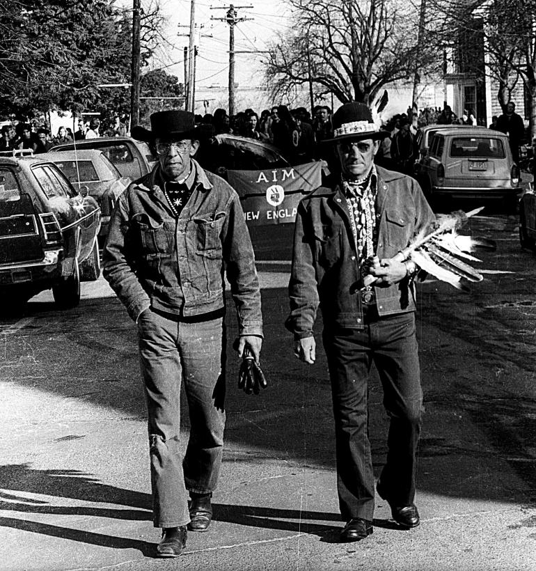 Two men walk down a city street in an undated black-and-white archival photo.