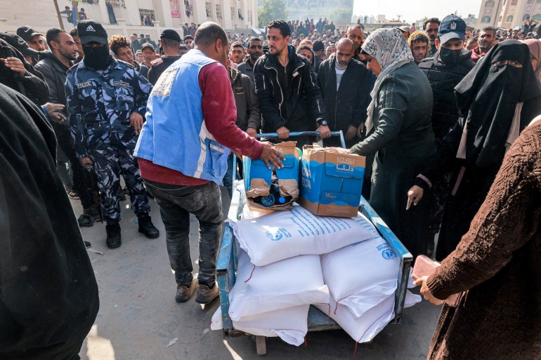 Workers of the United Nations Relief and Works Agency for Palestine Refugees (UNRWA) hand out flour rations and other supplies to people at an UNRWA warehouse in Rafah in the southern Gaza Strip on December 12
