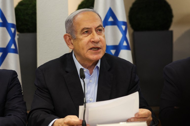 a man in a suit speaks in front of an Israeli flag